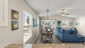 A spacious living area with a blue sofa, a dining table, and artwork on the walls.
