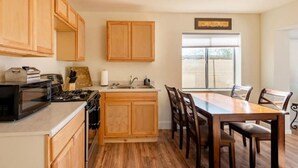 A kitchen with wooden cabinets, a microwave, stove, sink, and a dining table with chairs. - Cozy 1-bed condo for the perfect desert getaway (Black Canyon City)