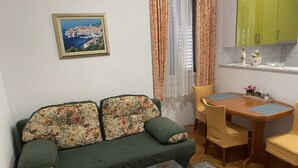 A compact living space with a sofa, a dining table, and a kitchen area.