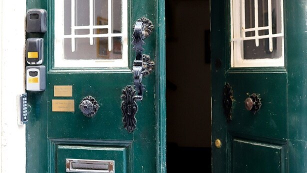 A green door with a window, a mail slot, and a doorbell.
