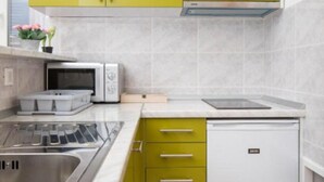 A compact kitchen with green cabinets, a microwave, a toaster, and a dishwasher.