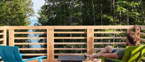 A wooden deck with a view of the sea, two chairs, and a small table.