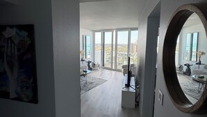 Ett rymligt vardagsrum med ett stort fönster, en rund spegel och en modern design.