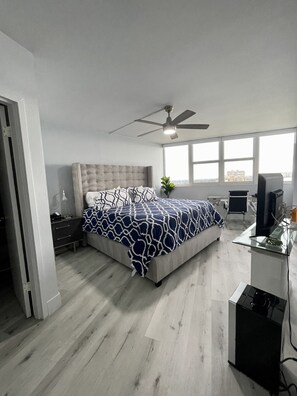 Une chambre moderne avec un grand lit, un bureau et un ventilateur de plafond.