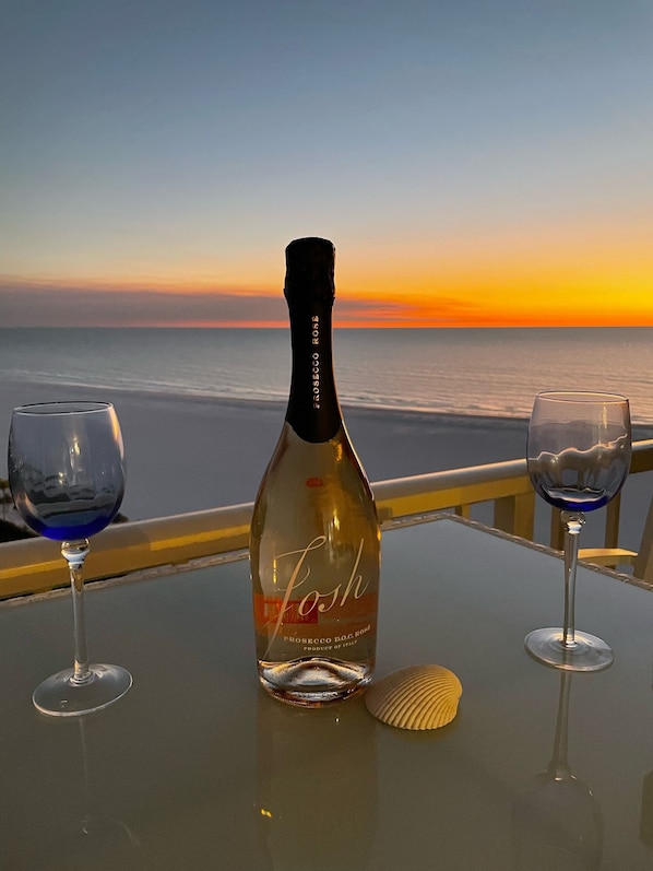 A bottle of prosecco DOC.Grosseto on a table with two glasses, one blue and one clear, and a seashell.