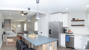 Una cocina moderna con una isla central, electrodomésticos de acero inoxidable y una escalera que conduce a un nivel superior.