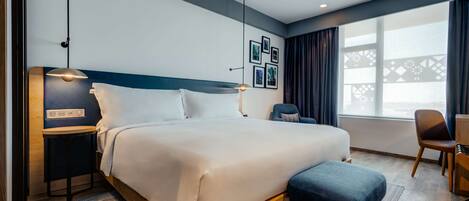 Una habitación de hotel moderna con una cama grande, una mesita de noche y un escritorio con una silla.
