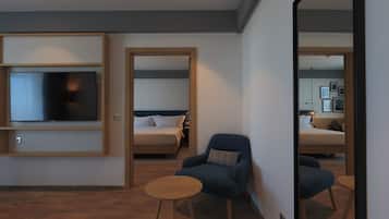 Une chambre d’hôtel moderne équipée d’un téléviseur à écran plat, d’un lit, d’un fauteuil bleu et d’une petite table en bois.
