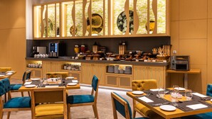 A modern dining area with wooden furniture, a buffet counter, and a decorative wall with patterned glass panels. - Hilton Garden Inn Casablanca Sud (Casablanca)