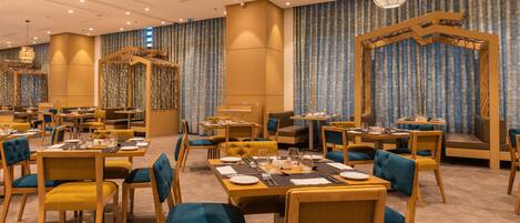 A spacious dining area with multiple tables and chairs, a central seating area with a unique wooden structure, and ambient lighting.