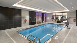Una piscina interior con carriles claramente marcados, una silla de socorrista y una zona de estar con vistas a la piscina.