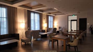 A hotel lobby with a seating area, tables, and a large mirror.