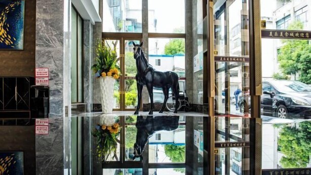 Un vestíbul amb un paviment de vidre, una estàtua d'un cavall i un vas amb flors.