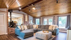 A spacious living room with a large sectional sofa, a fireplace, and a ceiling fan. - The Paso House | Family Fun For All (Redding)