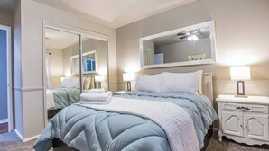 A bedroom with a bed, bedside tables, a mirror, and a ceiling fan. - The Paso House | Family Fun For All (Redding)