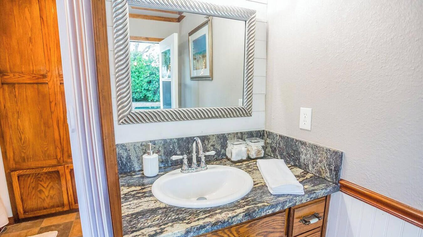 A bathroom with a marble sink, a large mirror, and a wooden door.
