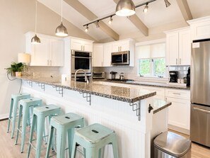 A modern kitchen with white cabinets, stainless steel appliances, and a granite countertop. - Sweeping Lake Views • Fire Pit • Hot Tub • Pets OK (Mooresville)