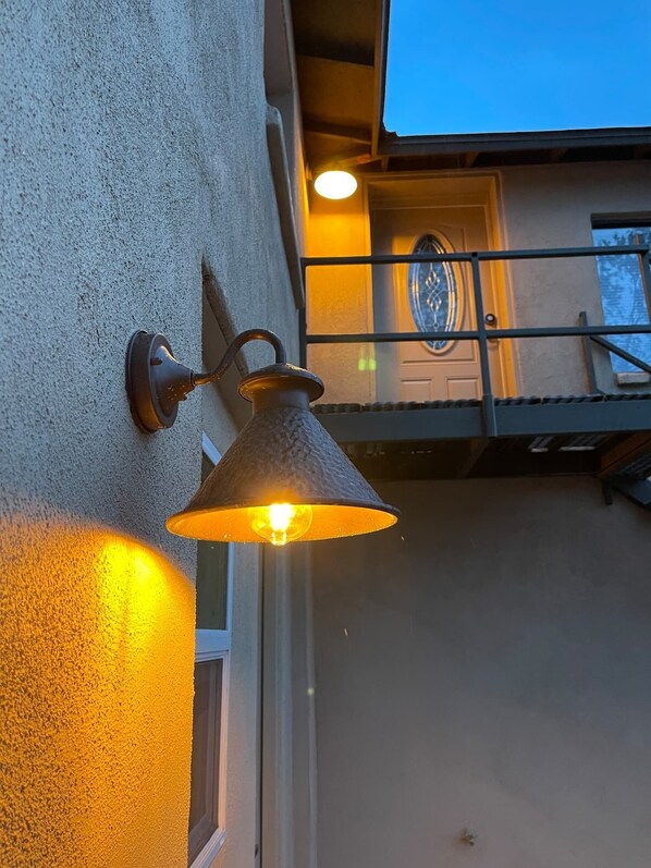 A wall-mounted outdoor light fixture with a conical shade, attached to a textured wall. - Perfect, fully furnished 1-bed condo (Black Canyon City)