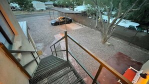 A staircase leading to a covered outdoor area with a car parked nearby. - Perfect, fully furnished 1-bed condo  (Black Canyon City)