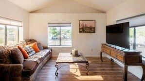 A living room with a sofa, a coffee table, a TV, and a window with a view. - Perfect, fully furnished 1-bed condo  (Black Canyon City)