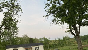 A small, single-story house with a gabled roof, a front porch, and a small front yard. - Country Cottage on the farm, peaceful, stars and fireflies! Sleeps 4! (Edmonton)