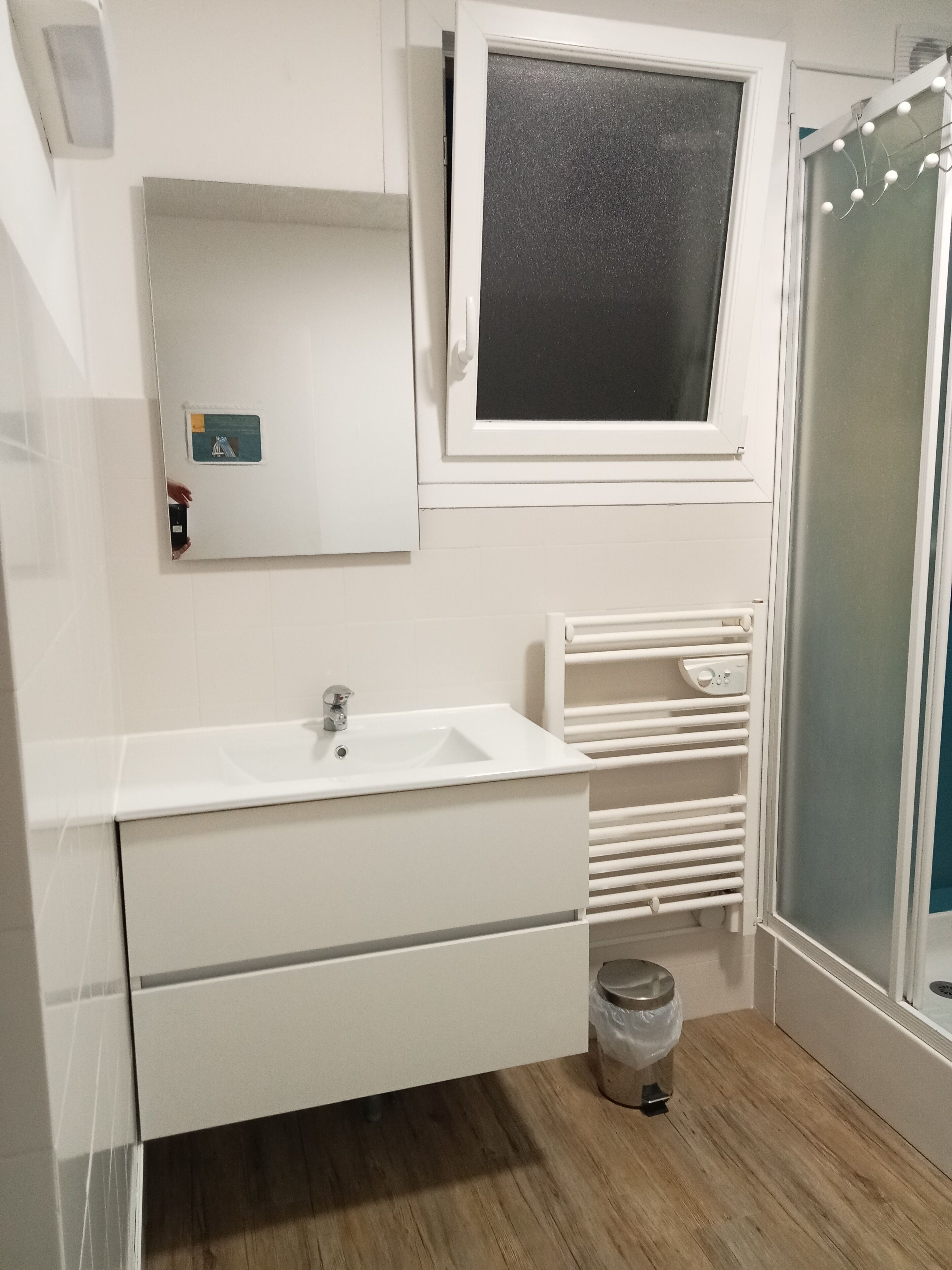 A bathroom with a white sink, mirror, and a window above the mirror.