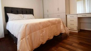 Ein Schlafzimmer mit Bett, Kleiderschrank und Schreibtisch.