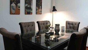 Ein Konferenzraum mit Glastisch, vier Polsterstühlen und drei gerahmten Kunstwerken an der Wand.