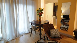 Uma sala de jantar com uma mesa, cadeiras, um vaso com flores e uma obra de arte moderna na parede.