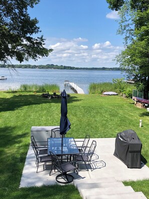 Un patio con mobili da esterno, un barbecue e vista su un lago.