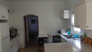 A compact kitchen with white cabinets, a stove, a sink, and a countertop. - 1-bed House Sleeps 2 With Parking (Sandys Parish)
