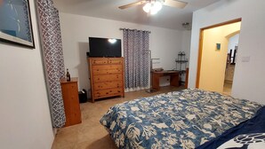 A bedroom with a bed, a dresser, a desk, a ceiling fan, and a television. - 1-bed House Sleeps 2 With Parking (Sandys Parish)