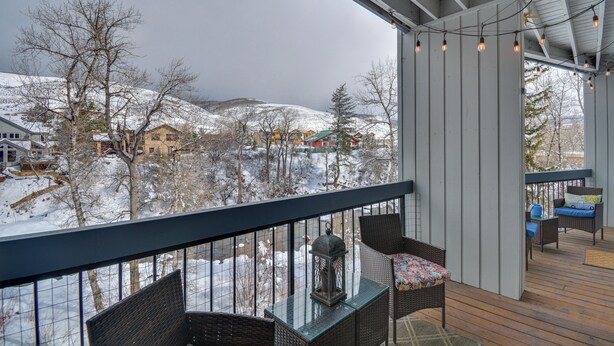 A covered outdoor area with wicker furniture and a view of a snowy landscape. - Private Riverside Ski Retreat  2/2 condo close to Beaver Creek and Vail (Avon)