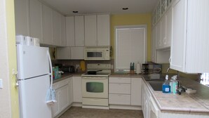 A compact kitchen with white cabinets, a refrigerator, a microwave, an oven, and a sink. - Peregrine's Nest (Smith River)