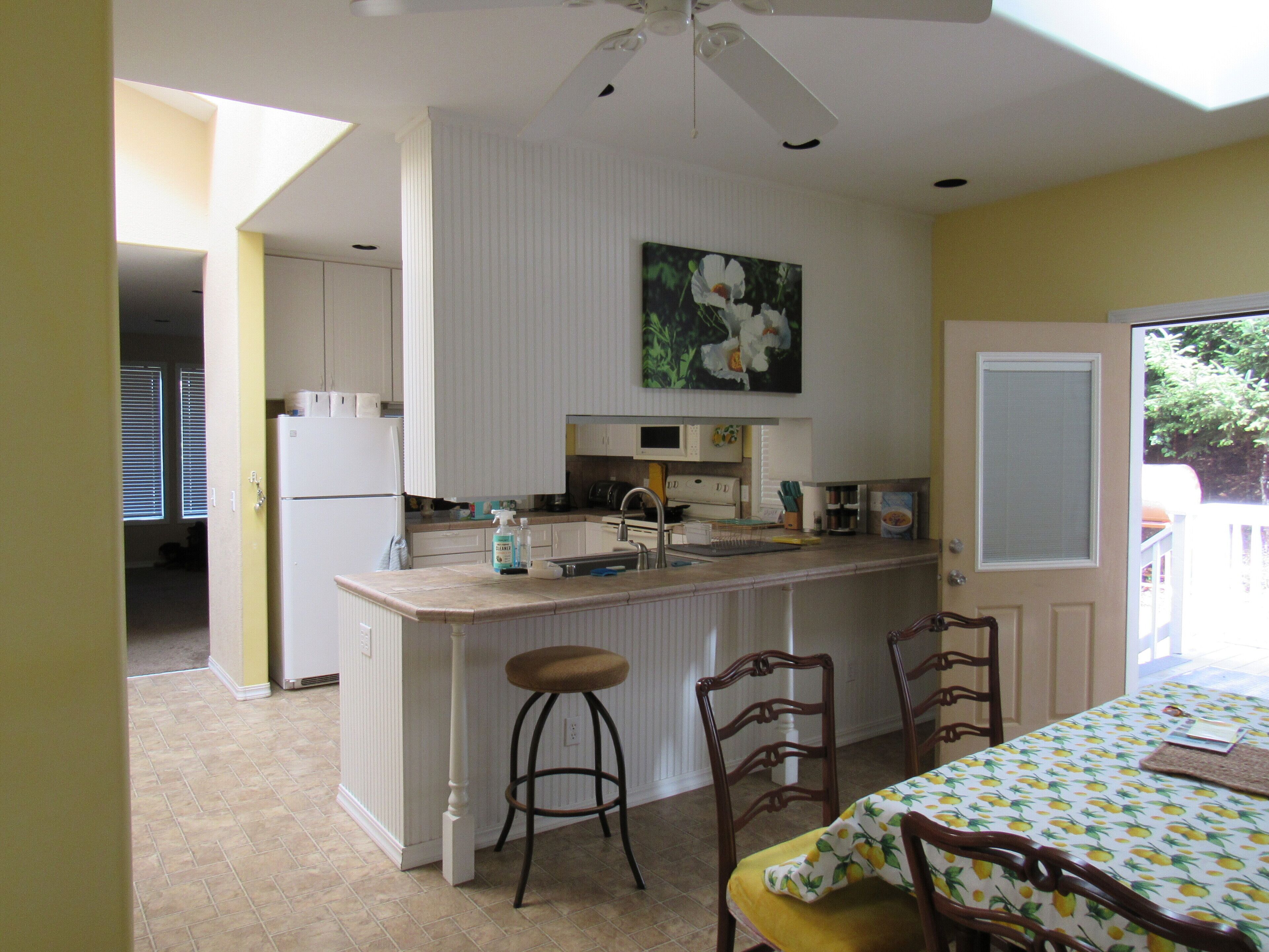 A compact kitchen with a central island, a dining area with a table and chairs, and a ceiling fan.