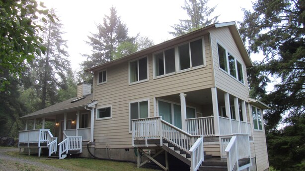 A two-story house with a porch and stairs leading to the entrance. - Peregrine's Nest (Smith River)