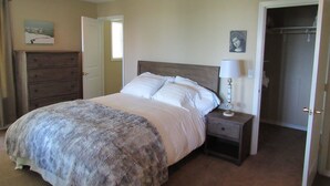 A bedroom with a bed, a nightstand, a dresser, and a door leading to a closet. - Peregrine's Nest (Smith River)