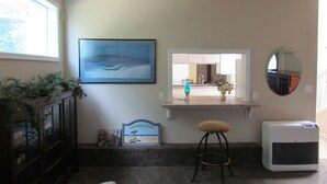 A bathroom with a window, a framed picture, a mirror, a towel, a heater, and a small shelf with a sign. - Peregrine's Nest (Smith River)