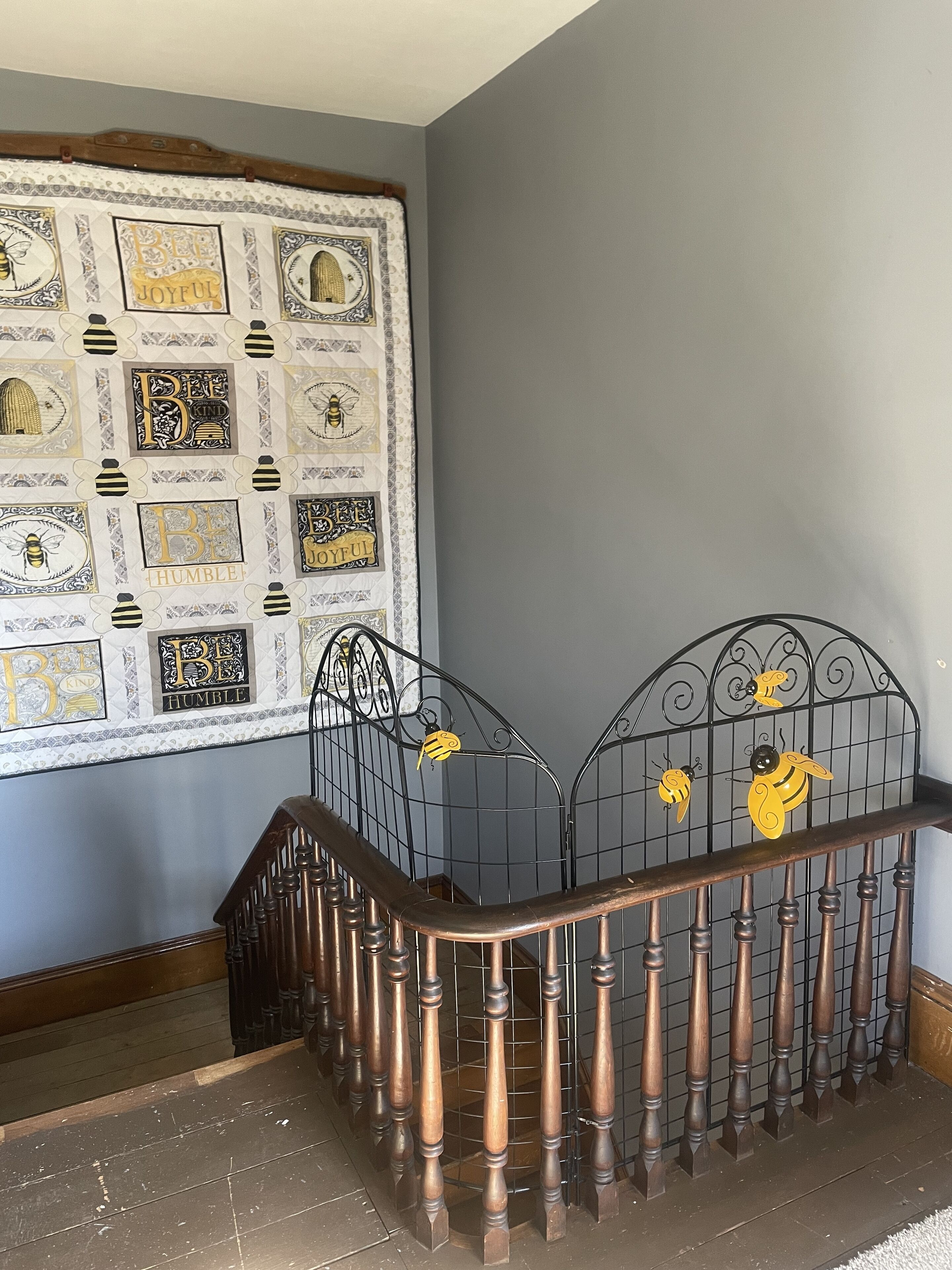 A staircase with a metal railing and a wall decorated with bee-themed wall art.