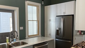 Una cocina moderna con armarios blancos, un refrigerador de acero inoxidable y un lavavajillas integrado.