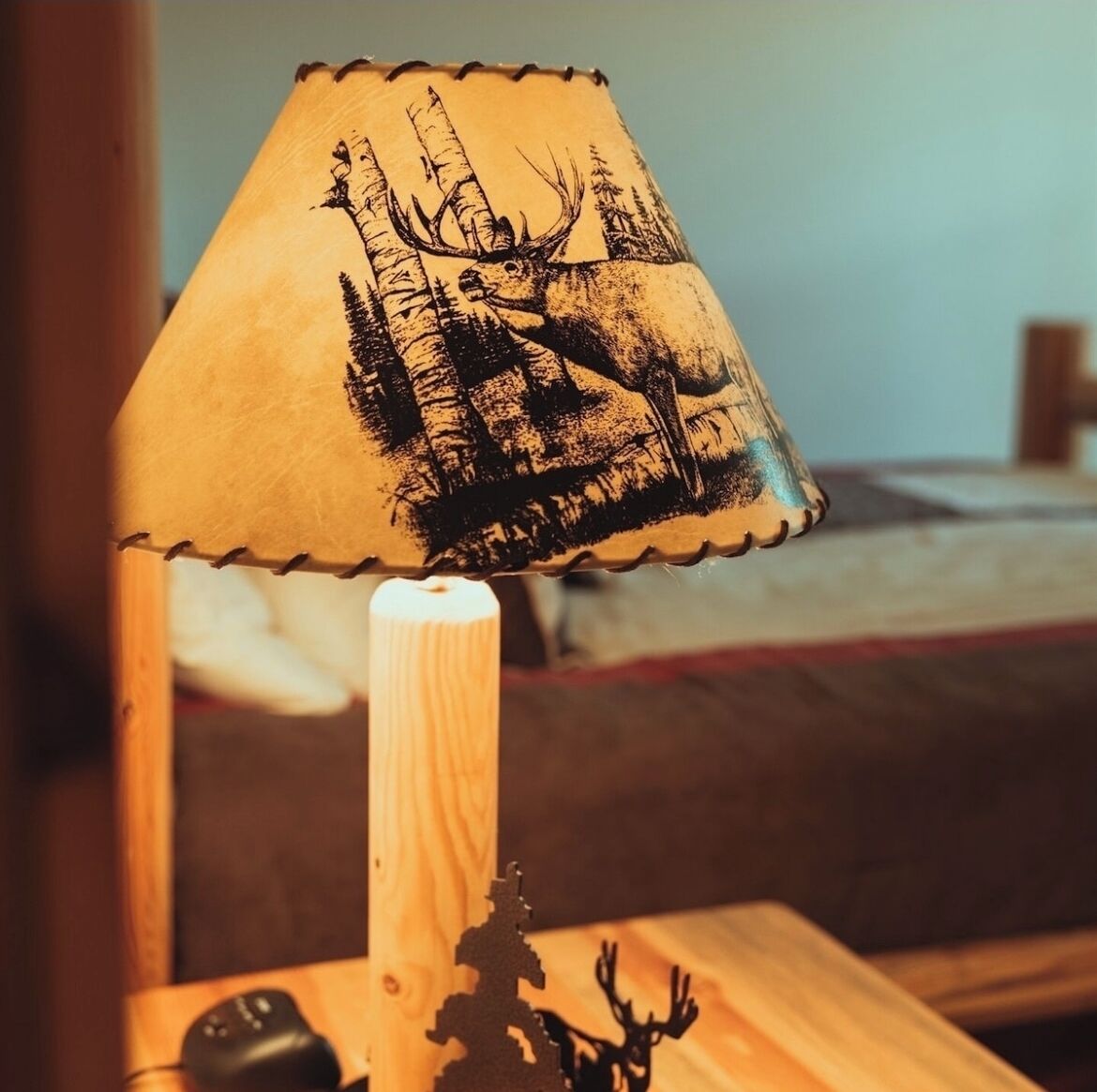 A lamp with a deer and forest scene on its shade.