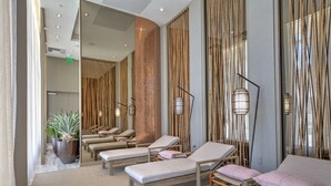 Et moderne spa-rum med flere solsenge, et stort spejl og en dekorativ væg med lodrette elementer.