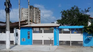 Un edificio con fachada azul y blanca, entrada con portón y pavimento de baldosas hexagonales.