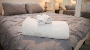 A neatly made bed with a rolled white towel in the center, a brown headboard, and a nightstand with a lamp. - ☀️Casita bonita 🏖 Villa with 4beds/3 bath and HEATED pool 🌴🔥 (Sunrise)