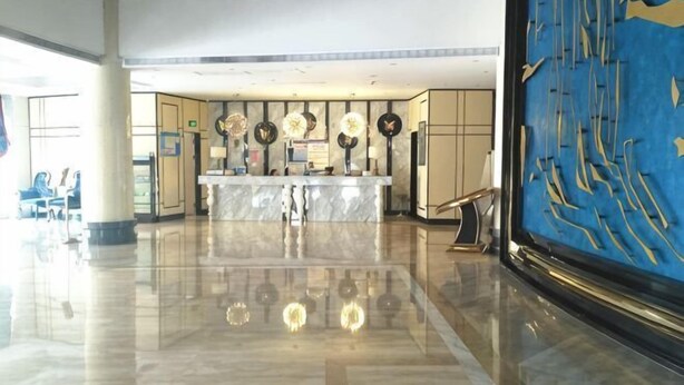 Eine Hotelhalle mit einem мрамор Reception Desk, einem großen blauen Kunstwerk auf der rechten Seite und einem polierten Boden.