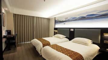 Quarto de hotel com duas camas, uma escrivaninha e um quadro de uma paisagem.
