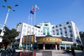 Een hotel met een centrale ingang, verschillende verdiepingen en vlaggen.