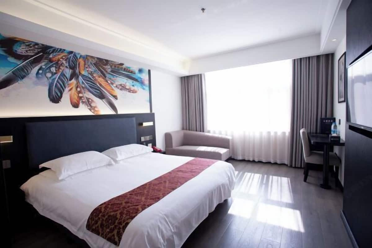 Habitación de hotel con una cama grande, un sofá, un escritorio y un cuadro en la pared.