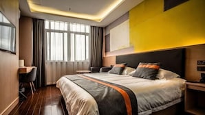 Ein Hotelzimmer mit einem großen Bett, einem Schreibtisch und einem fenster mit Vorhängen.