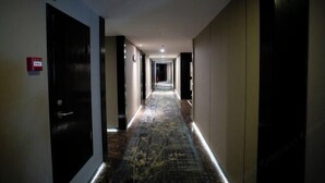 Ein Hotelgang mit Teppichmuster, Türen an beiden Seiten und einer an der Decke befestigten Überwachungskamera.